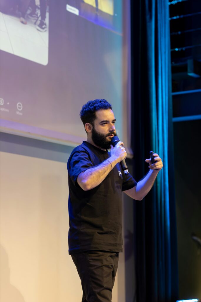 Male speaker presenting on stage at a conference, engaging audience.